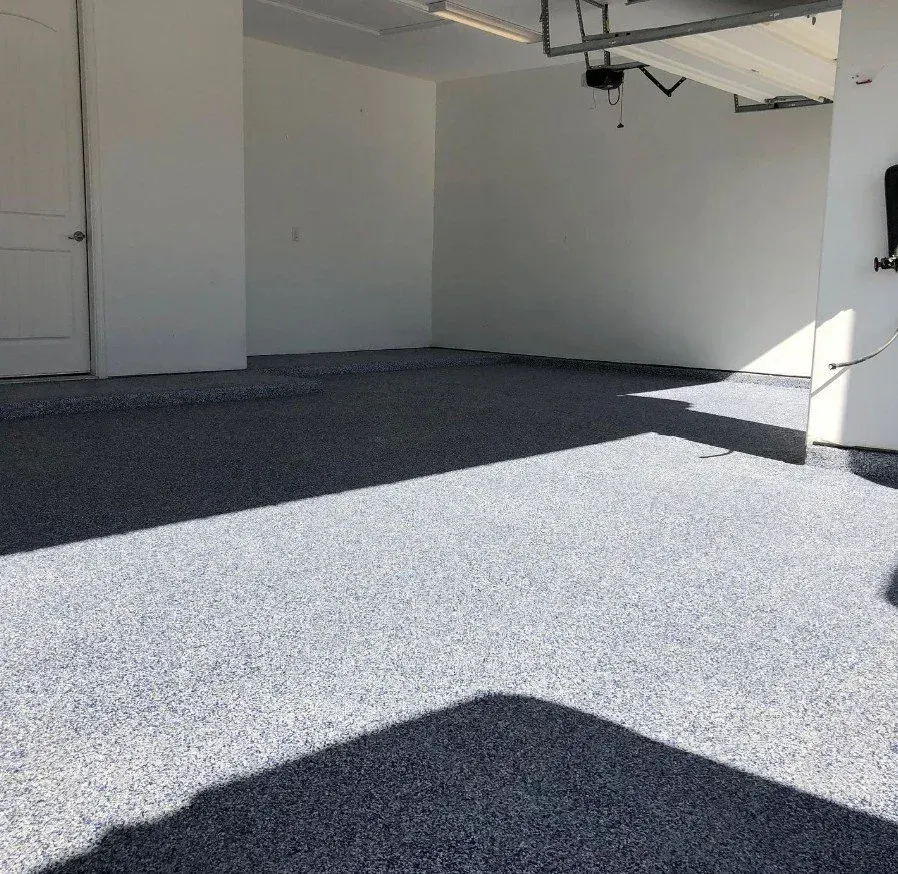 Empty covered patio with gray speckled flooring and sunlight casting shadows on white walls