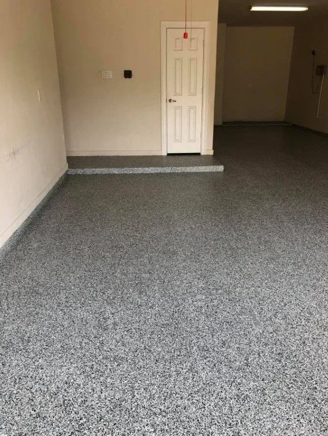 Empty carpeted room with white walls, a closed white door, and a small step up at the back.