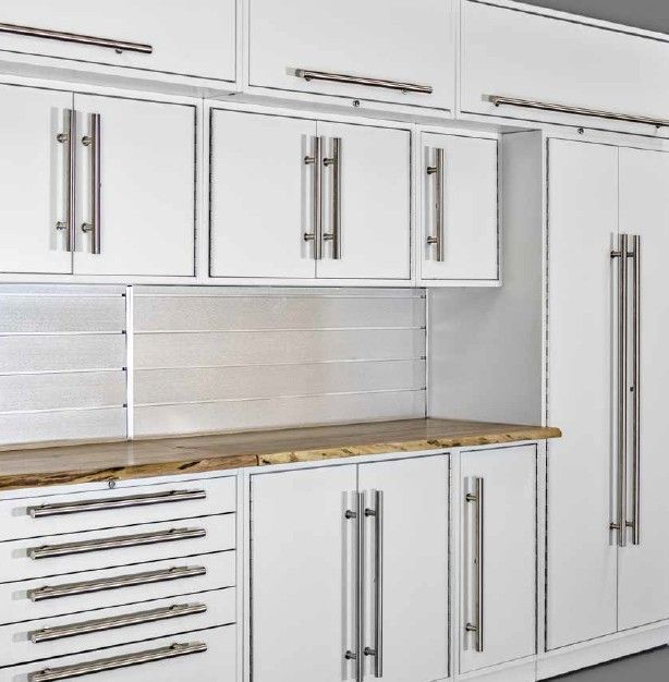 Clean white ProSlat LUX garage cabinetry with a warm live edge wood countertop and modern metal backsplash, offering a bright and functional workspace.  Designed by Global Garage Flooring & Design of Houston