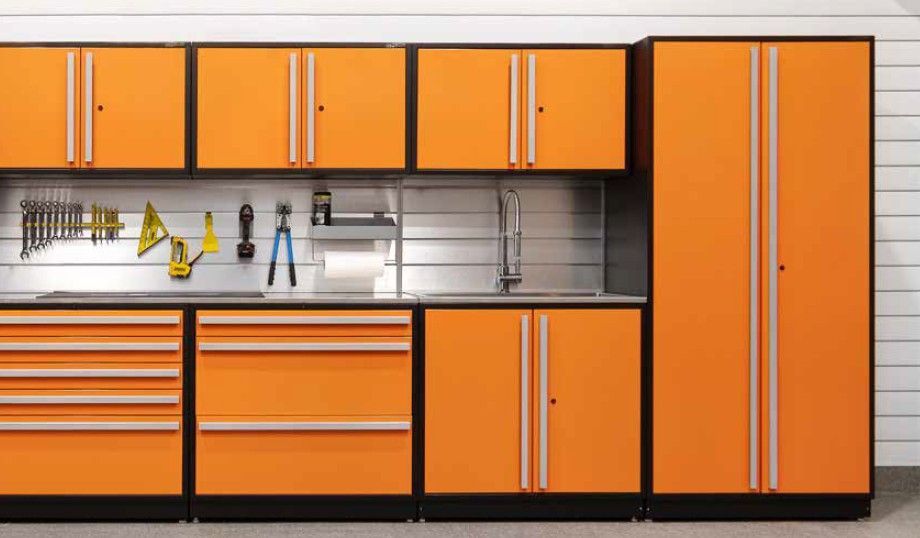 Vibrant orange ProSlat FusionPlus garage cabinets with a full tool wall and built‑in sink, offering a functional and visually striking workspace.  Designed by Global Garage Flooring & Design of Houston.