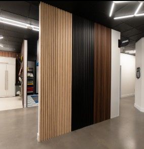 A contemporary vertical slat wall featuring ProSlat Decorative Wall Panels, combining light, dark, and black wood tones—perfect for elevating modern garage or showroom interiors.