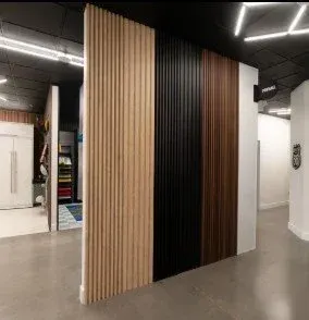 Check out a contemporary showroom display using a ProSlat ProPanel architectural divider wall, showing off a seamless transition from light wood slats to textured black panels