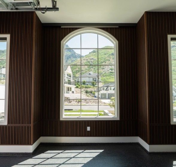 Bright room with large arched window, ProSlat Decorative Panel walls, and mountain view beyond.
