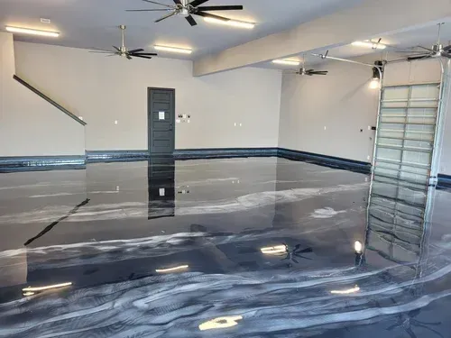 Explore a massive interior garage space featuring a high-gloss, mirror-like onyx metallic epoxy floor accented by shimmering silver veins in Metallic floor