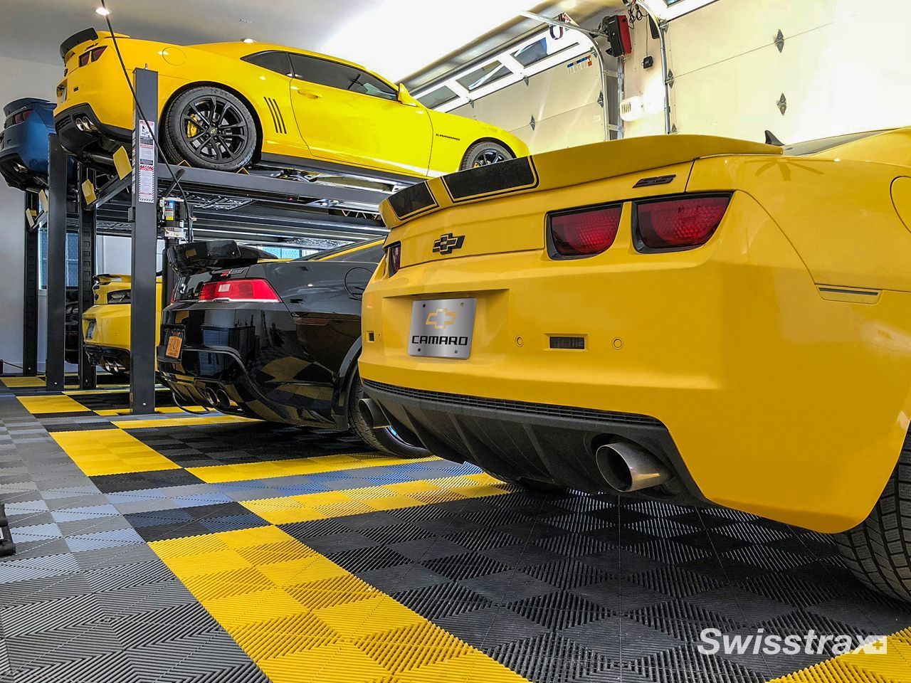 Check out a garage to see a stunning yellow sports cars sitting on a custom multi-toned yellow, grey and black SwissTrax tile garage floor, beautifully installed to match the vehicles.