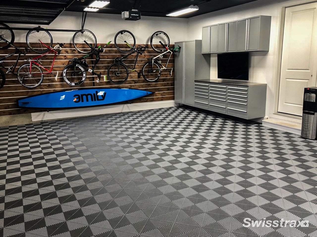Check out this garage to see an organized home garage featuring high-end bicycles and a kayak mounted on a wood accent wall, all perfectly complemented by a grey and black checkered SwissTrax interlocking tile floor.