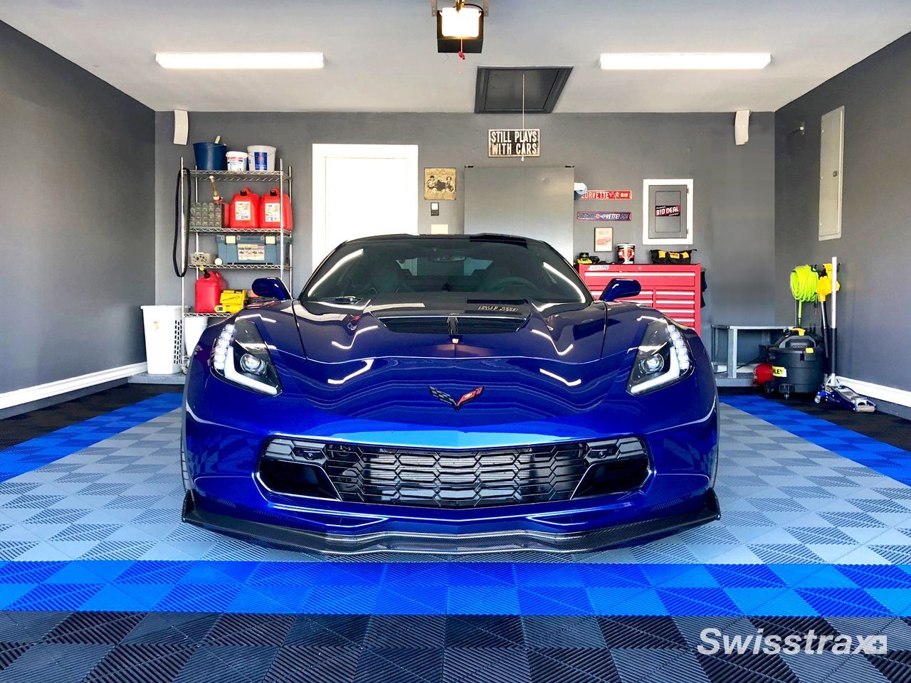 Check out this garage to see a stunning blue Corvette sitting on a custom multi-toned blue and black SwissTrax tile garage floor, beautifully installed to match the vehicle.