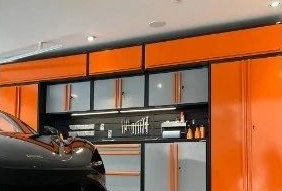 Orange and black garage with built-in cabinets and a car parked inside