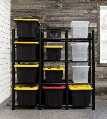 Black and clear storage bins with yellow lids on a black shelving unit against a wood wall.