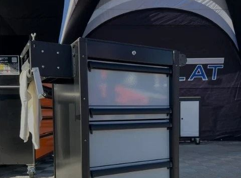Large black equipment cabinet with shelves inside a tented event space
