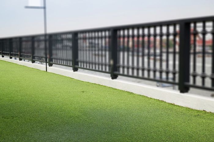 A black fence surrounds a lush green field.