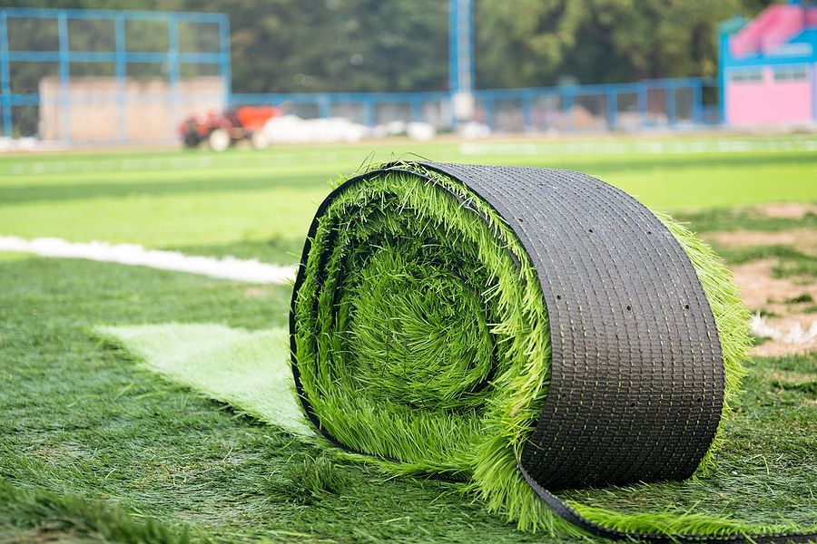 A roll of artificial grass is sitting on top of a soccer field.