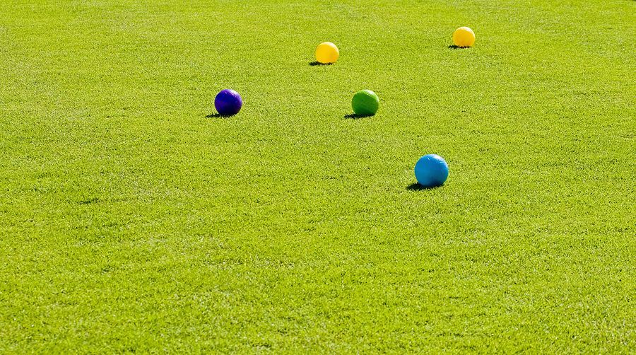 A row of croquet balls on a lush green field