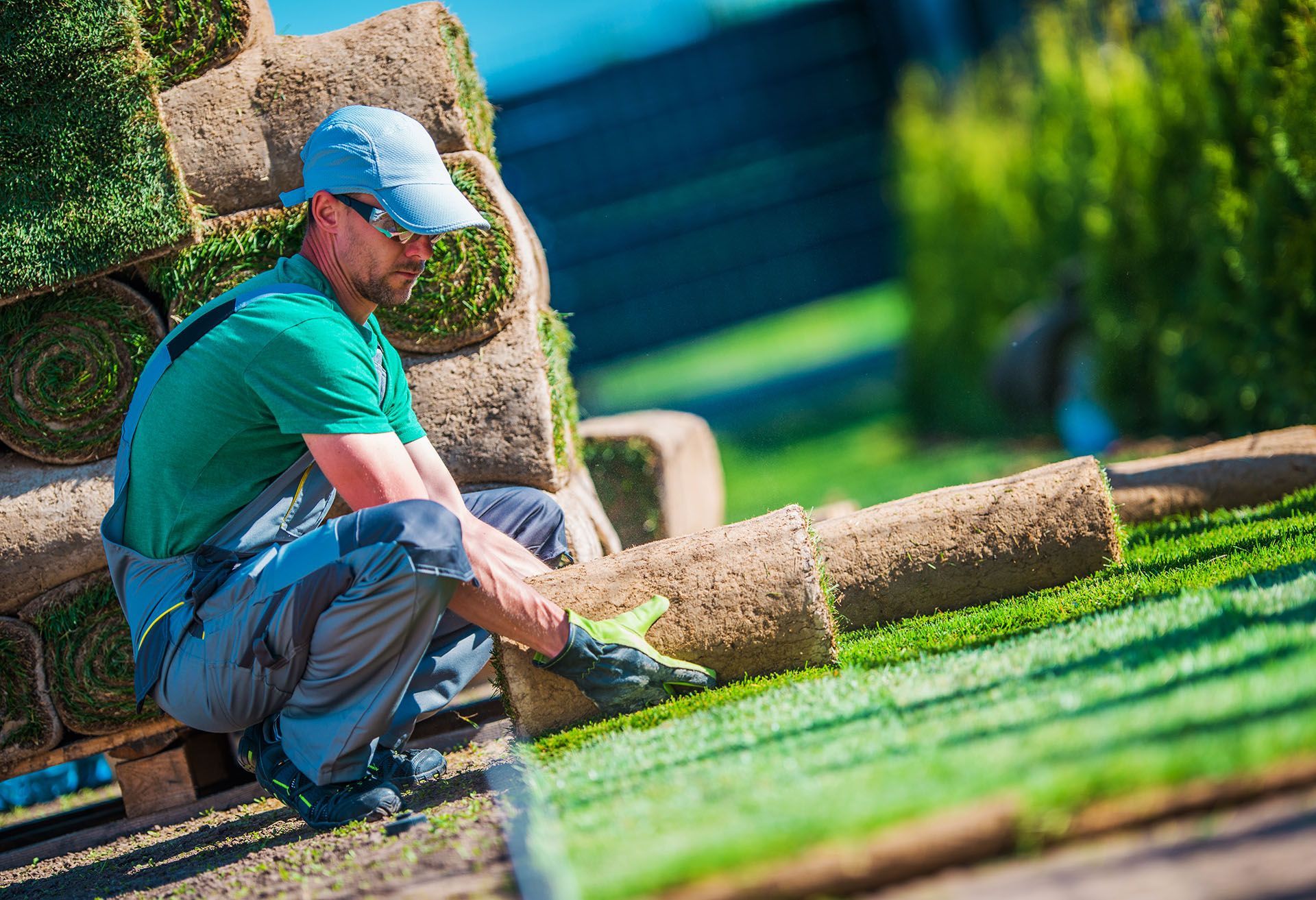 A man is working on a lawn with rolls of grass.