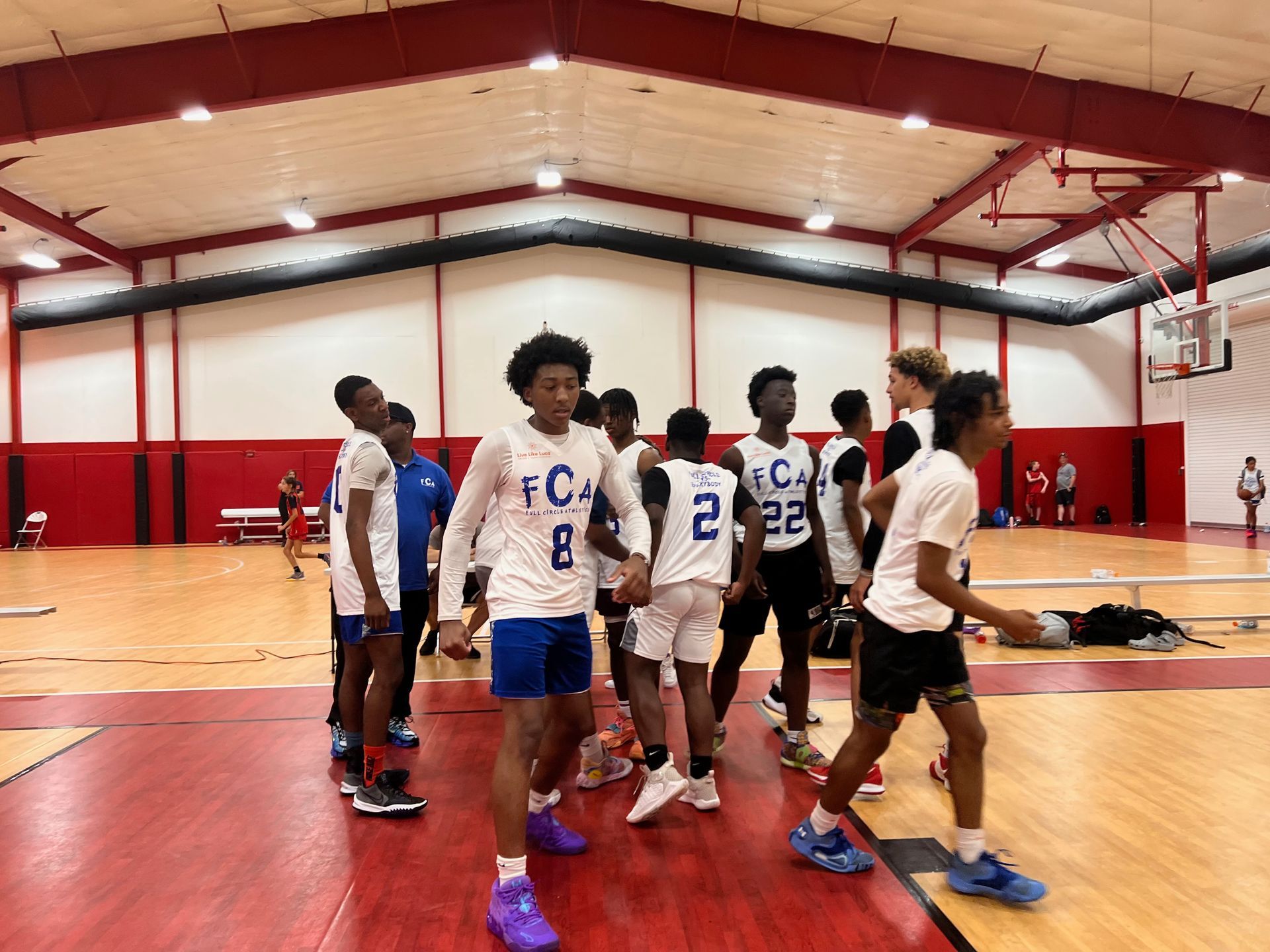 Basketball players in white and blue jerseys on a court. 