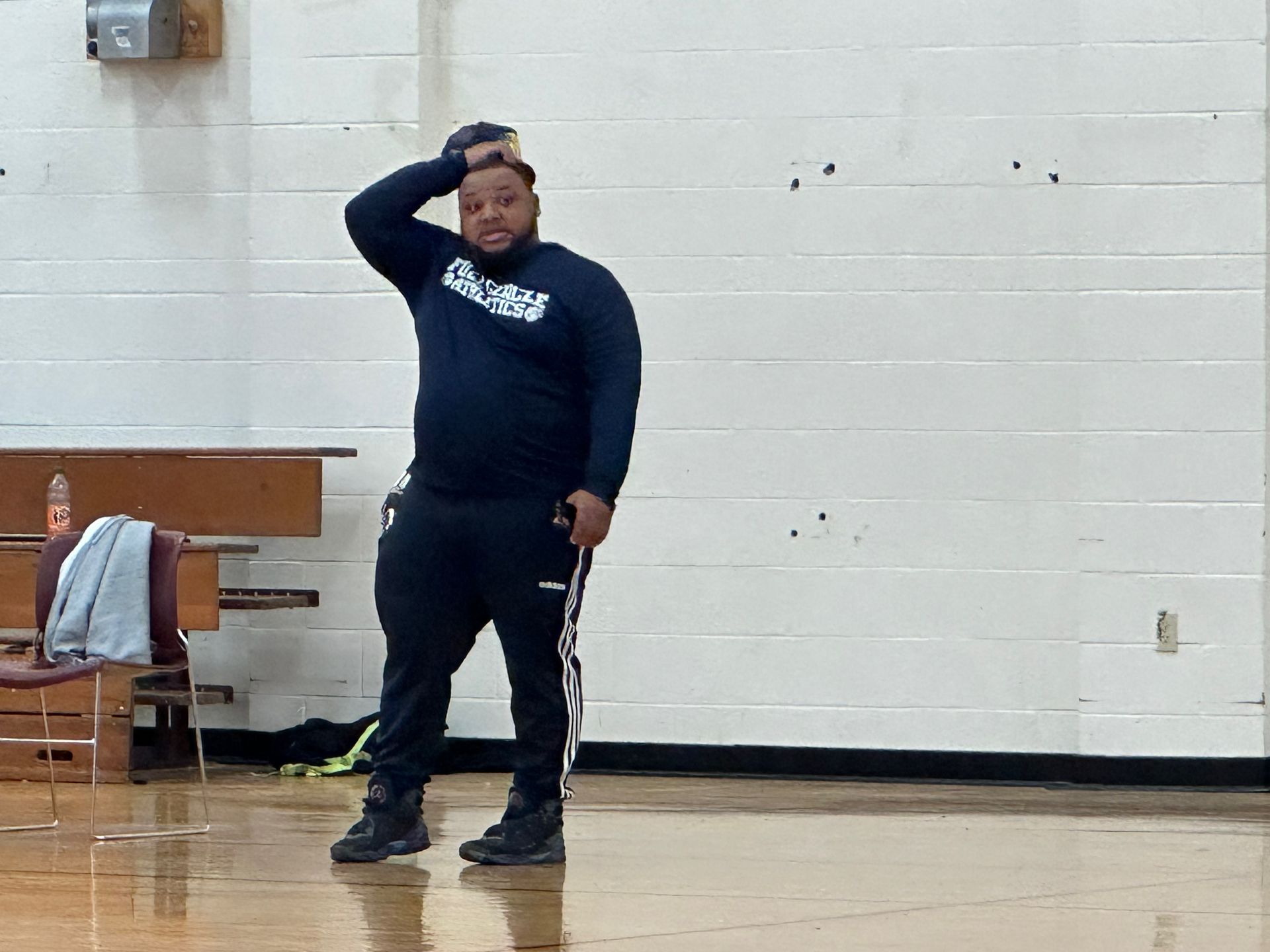 Man in athletic wear in a gym, scratching his head.