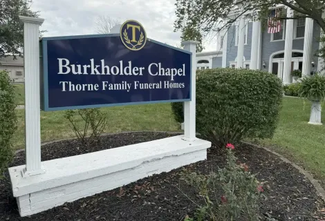 Burkholder Chapel Thorne Family Funeral Home sign by a landscaped entrance