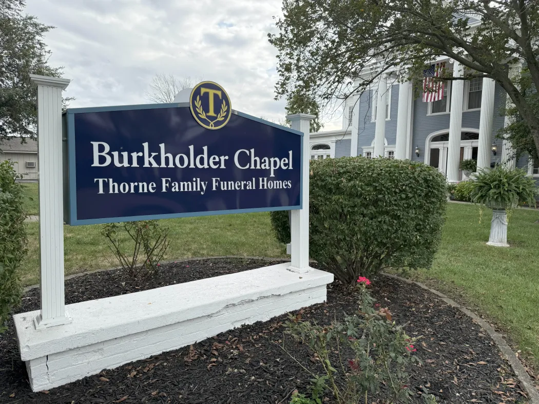 Burkholder Chapel Thorne Family Funeral Home sign beside landscaping and a white building