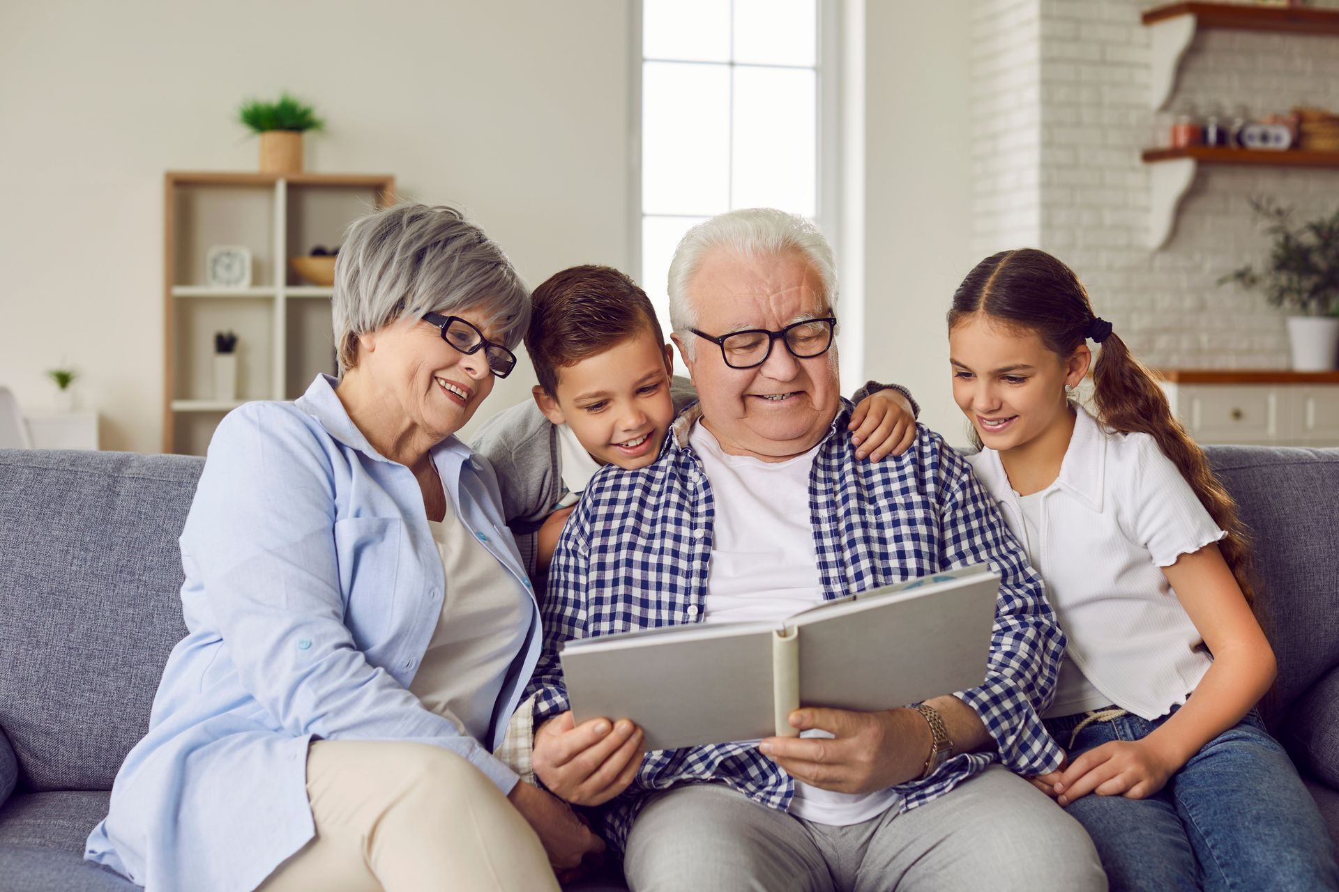 Family gathered on a couch, smiling and looking at a photo album together in a cozy living room
