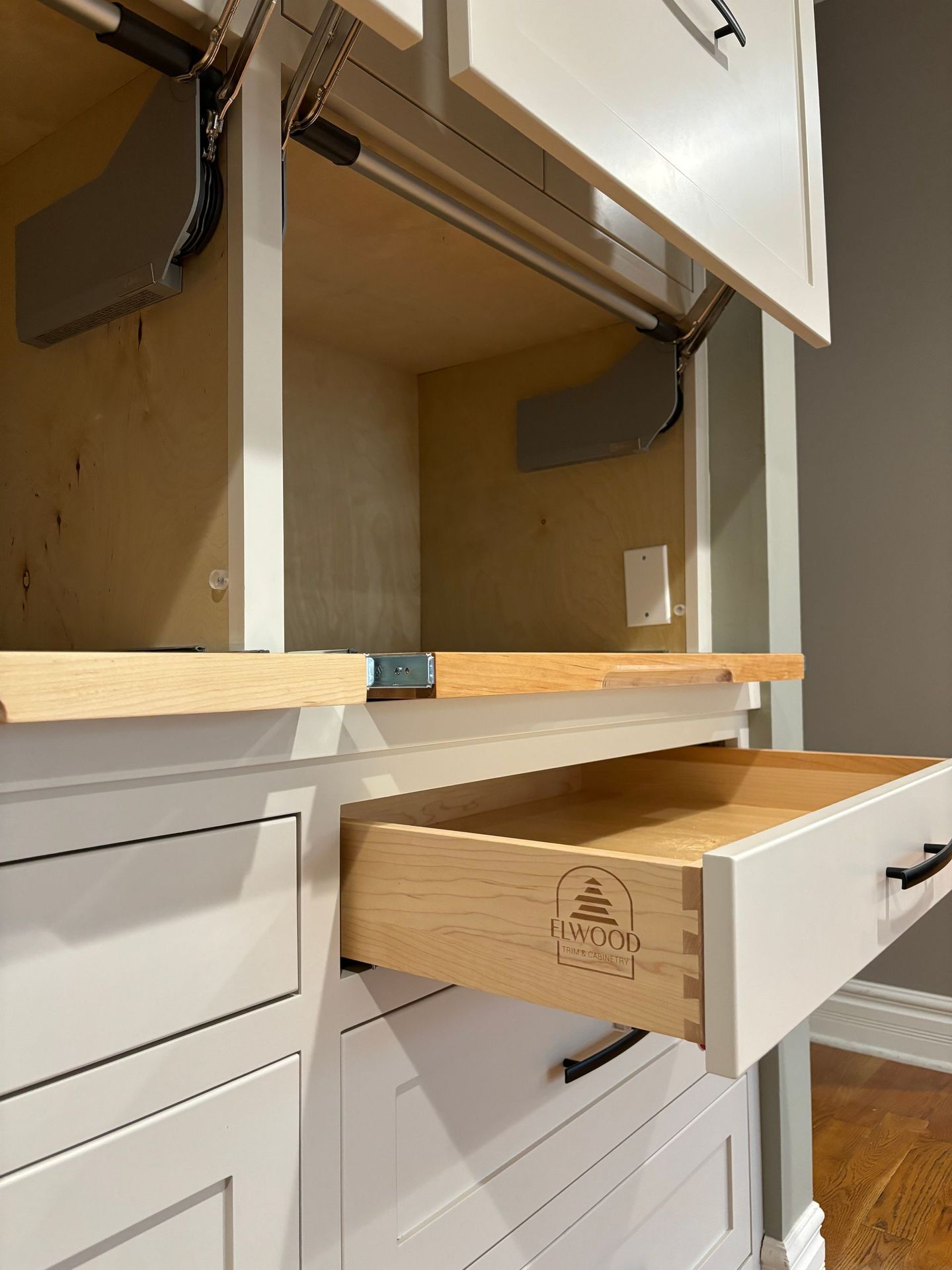 White kitchen cabinet with open drawer and lift mechanism.