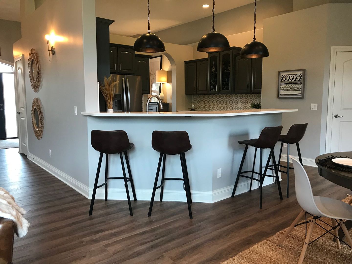 Kitchen with dark cabinets, bar with stools, and pendant lights.