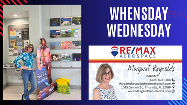 A woman is standing next to a card that says re / max aerospace