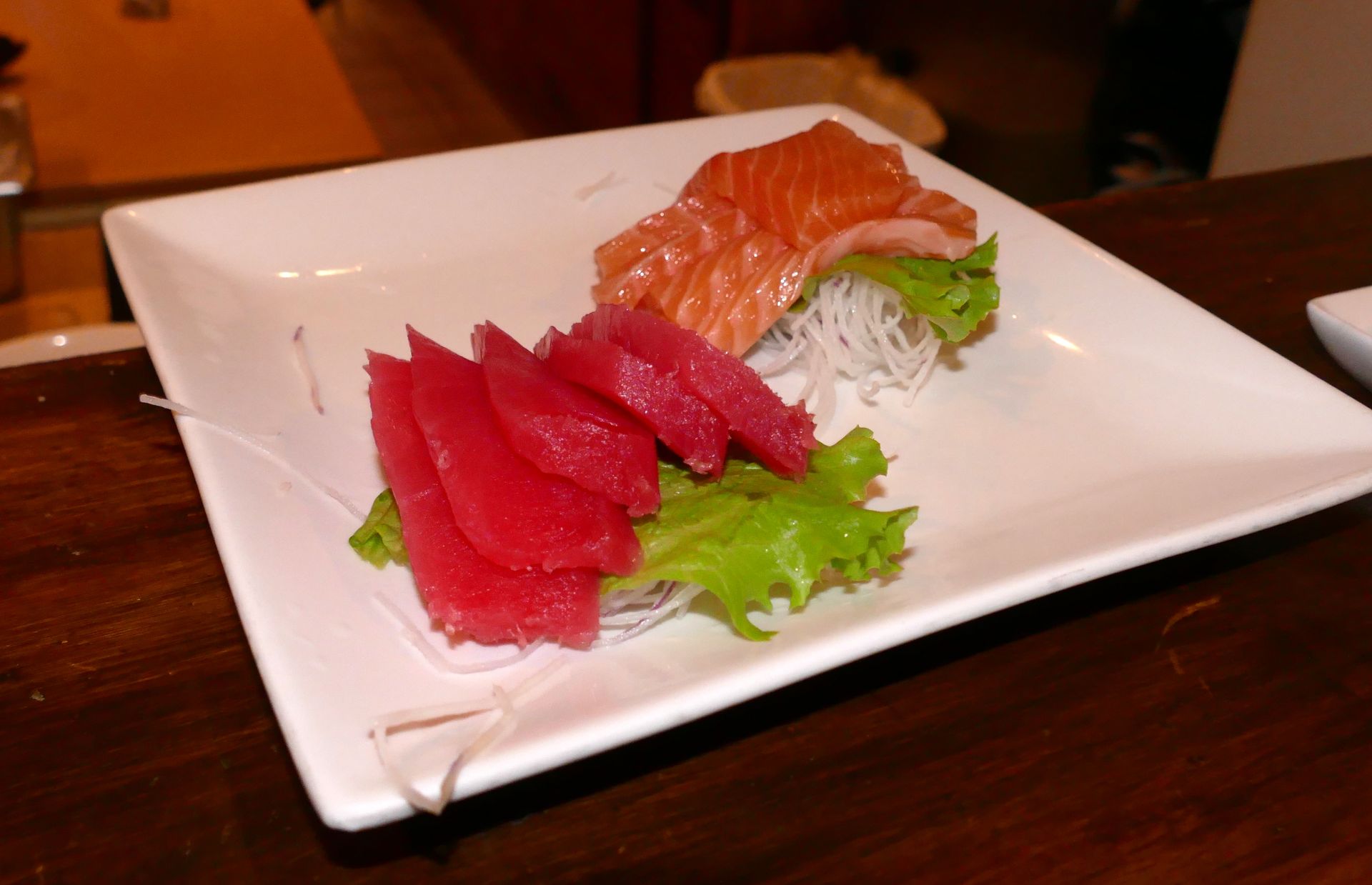 Sushi sashimi platter with red tuna and salmon slices on a white plate