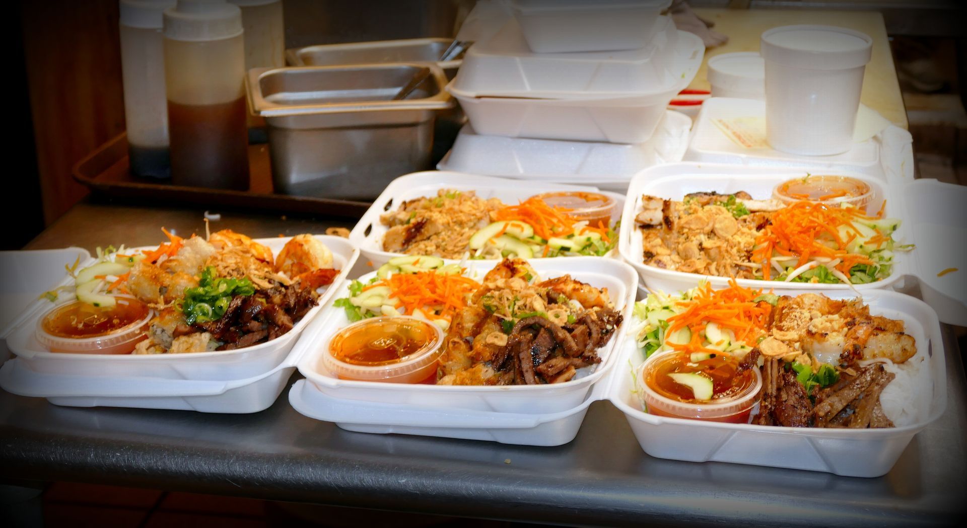 Takeout containers filled with noodles, rice, and vegetables arranged on a counter