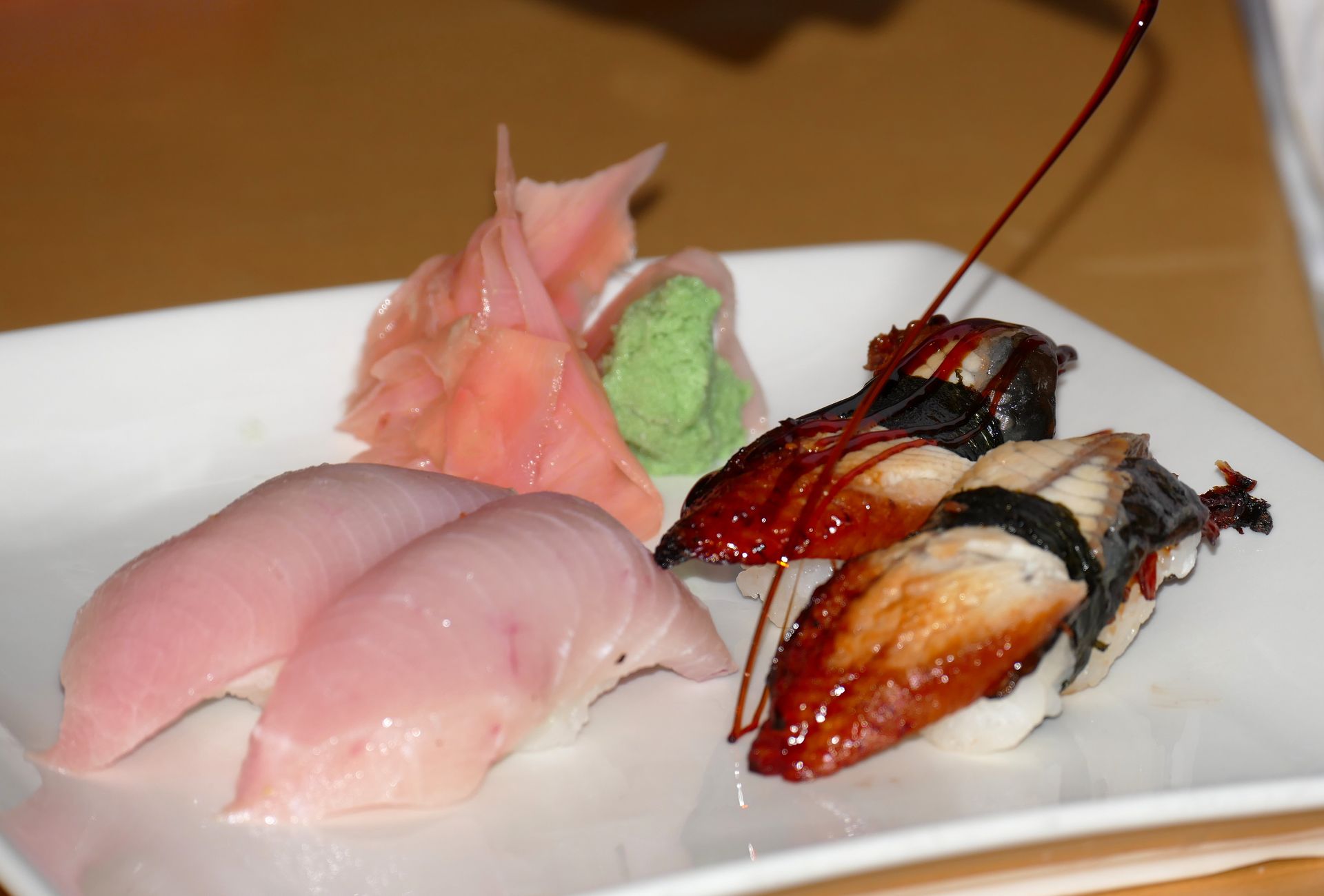 Sushi platter with pink sashimi, green wasabi, and grilled pieces on a white plate