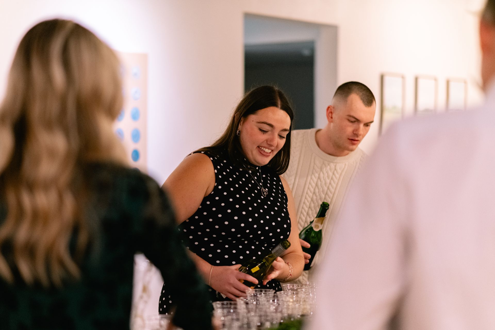 Lily laughing with guests as Bridgett pours wine