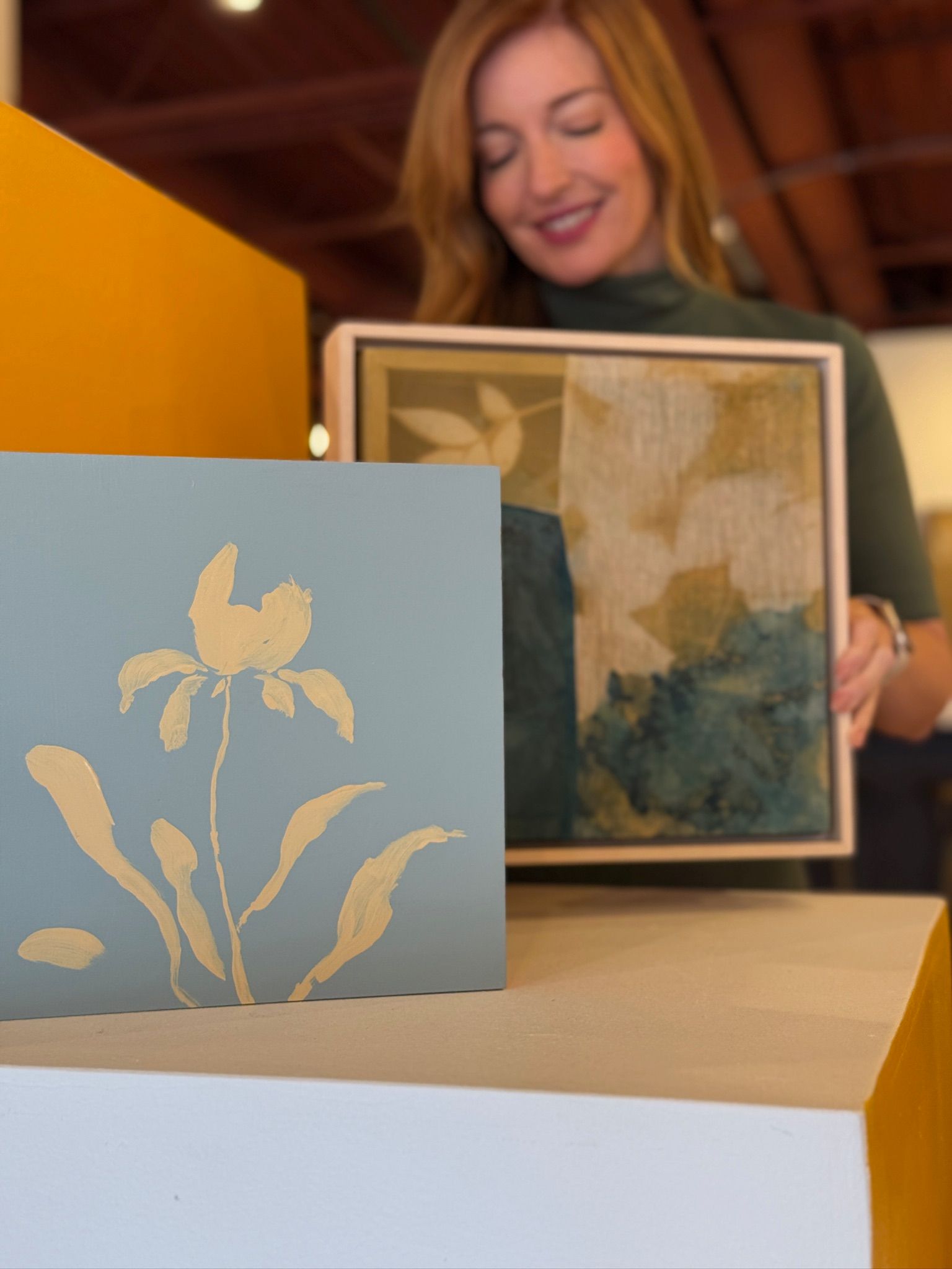 Liz holding two pieces of art
