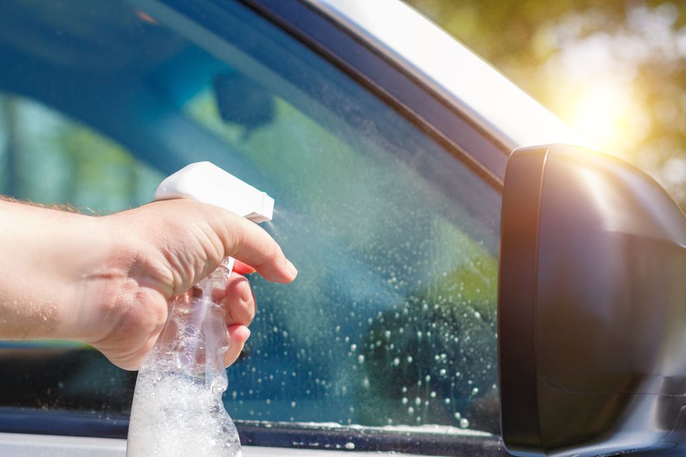 A Person is Cleaning the Windshield of a Car With a Spray Bottle — Sue's Clear Water in Mackay, QLD