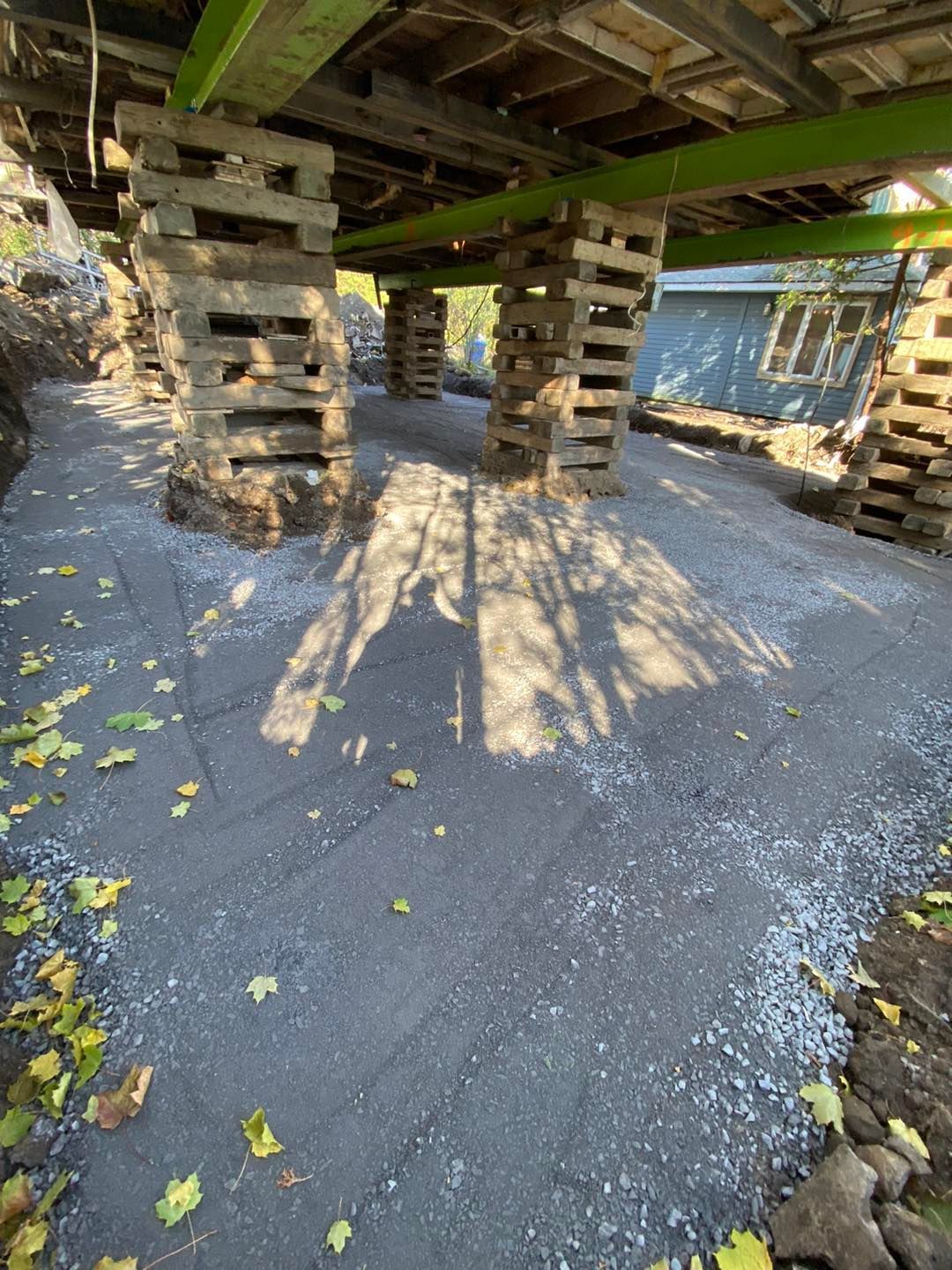 Maison surélevée sur blocs de béton empilés, sol de gravier.