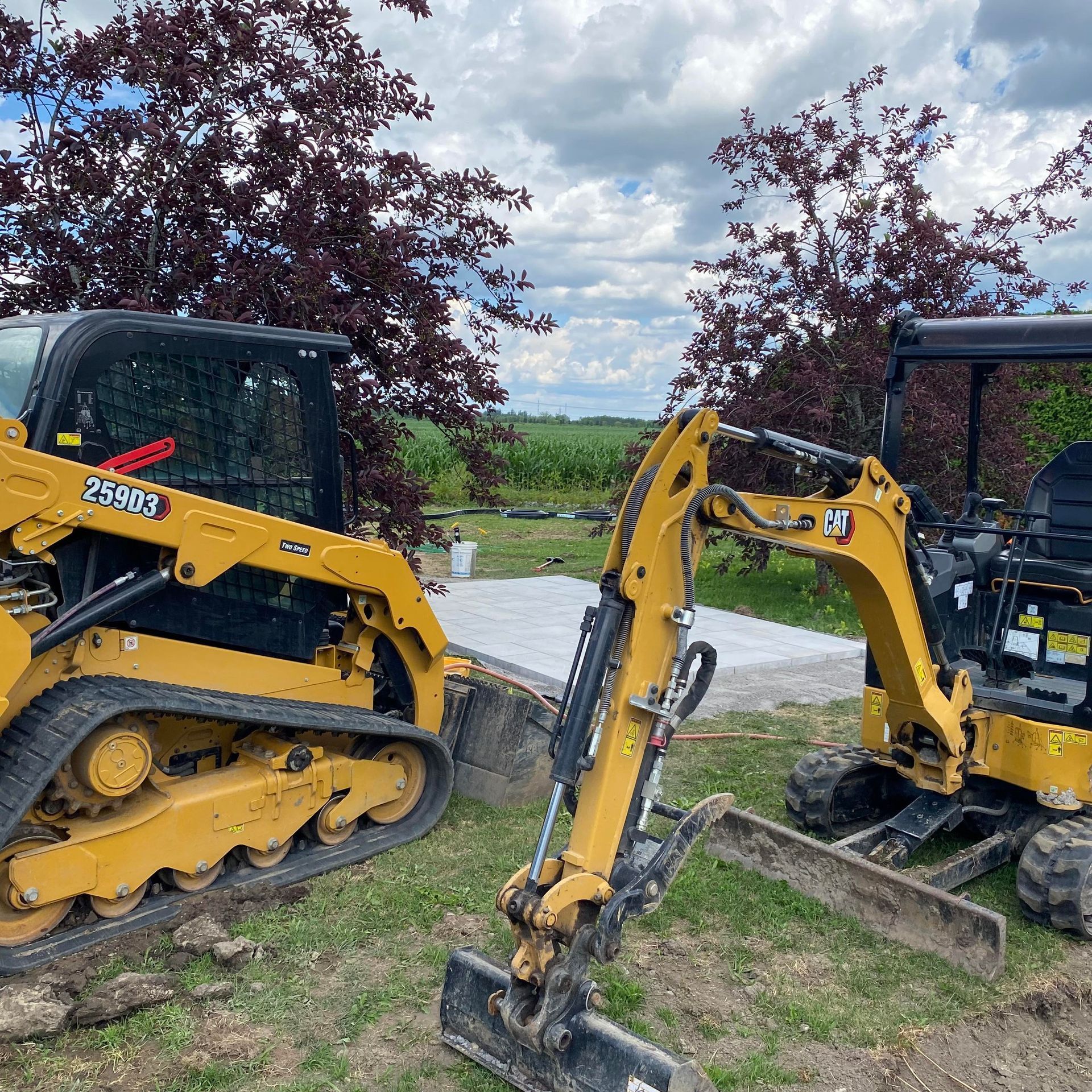 Matériel de chantier jaune : une chargeuse compacte et une mini-pelle sur un chantier.