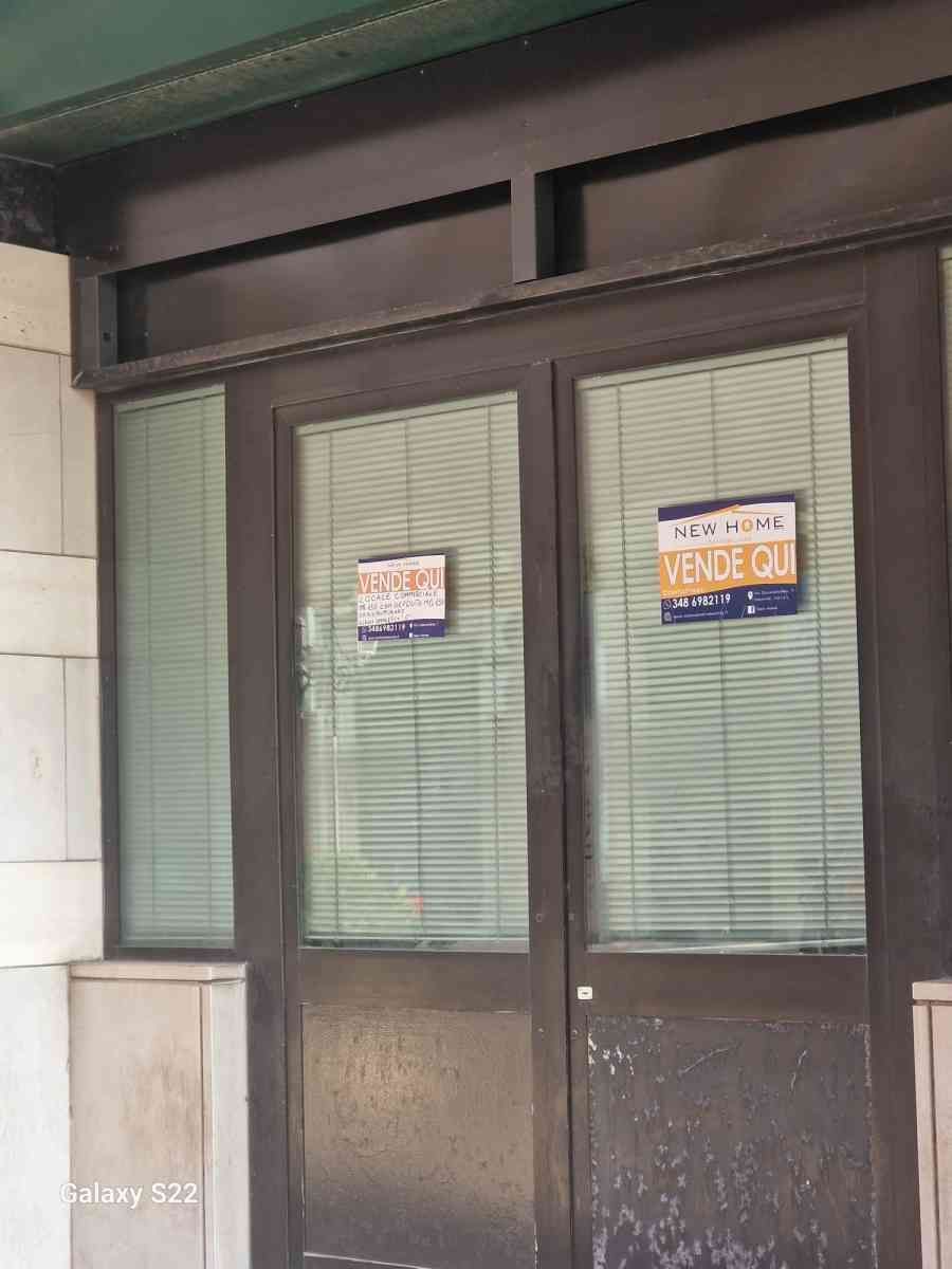 Vetrina con porte e finestre in vetro, con due cartelli affissi e tende all'interno.