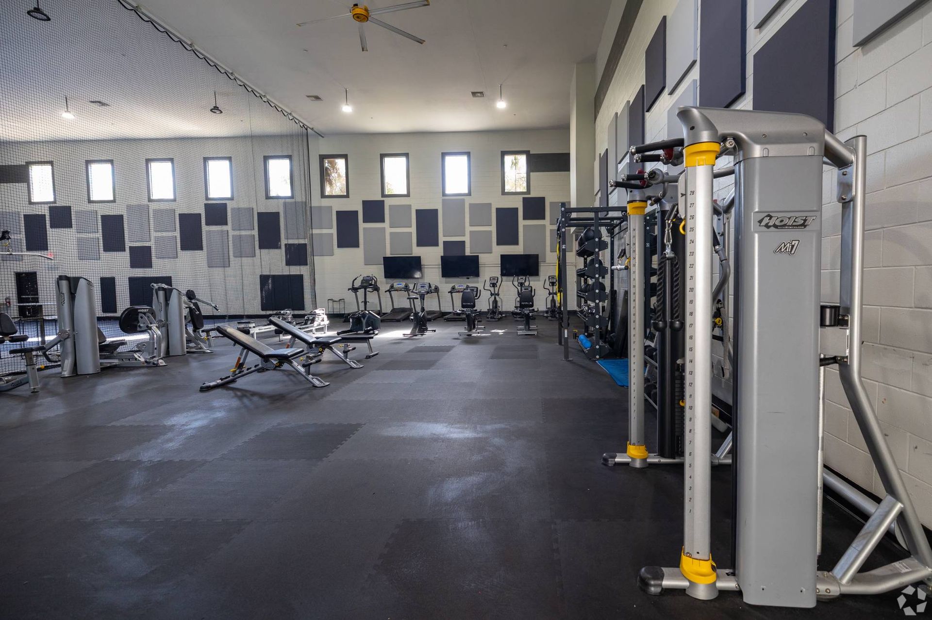Indoor gym with cardio machines, free weights, and weight machines at Uptown Village Apartments in Gainesville, FL.