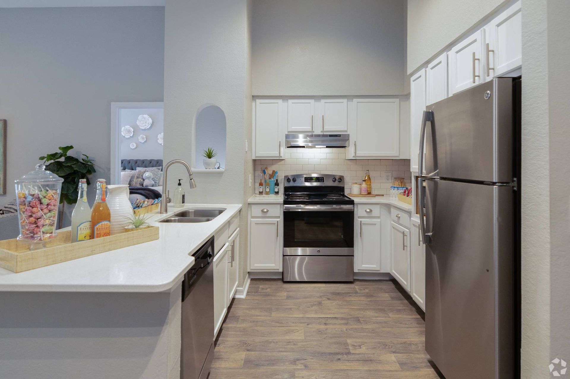 Bright kitchen in an apartment with white cabinets, stainless-steel appliances, island sink at Uptown Village Apartments in Gainesville, FL.