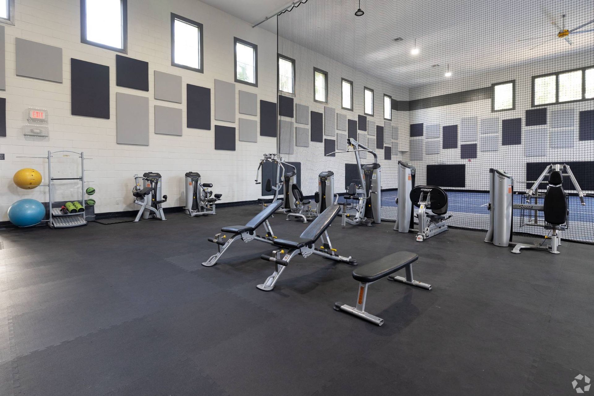 Indoor apartment gym with benches, weight machines, and cardio equipment at Uptown Village Apartments in Gainesville, FL.