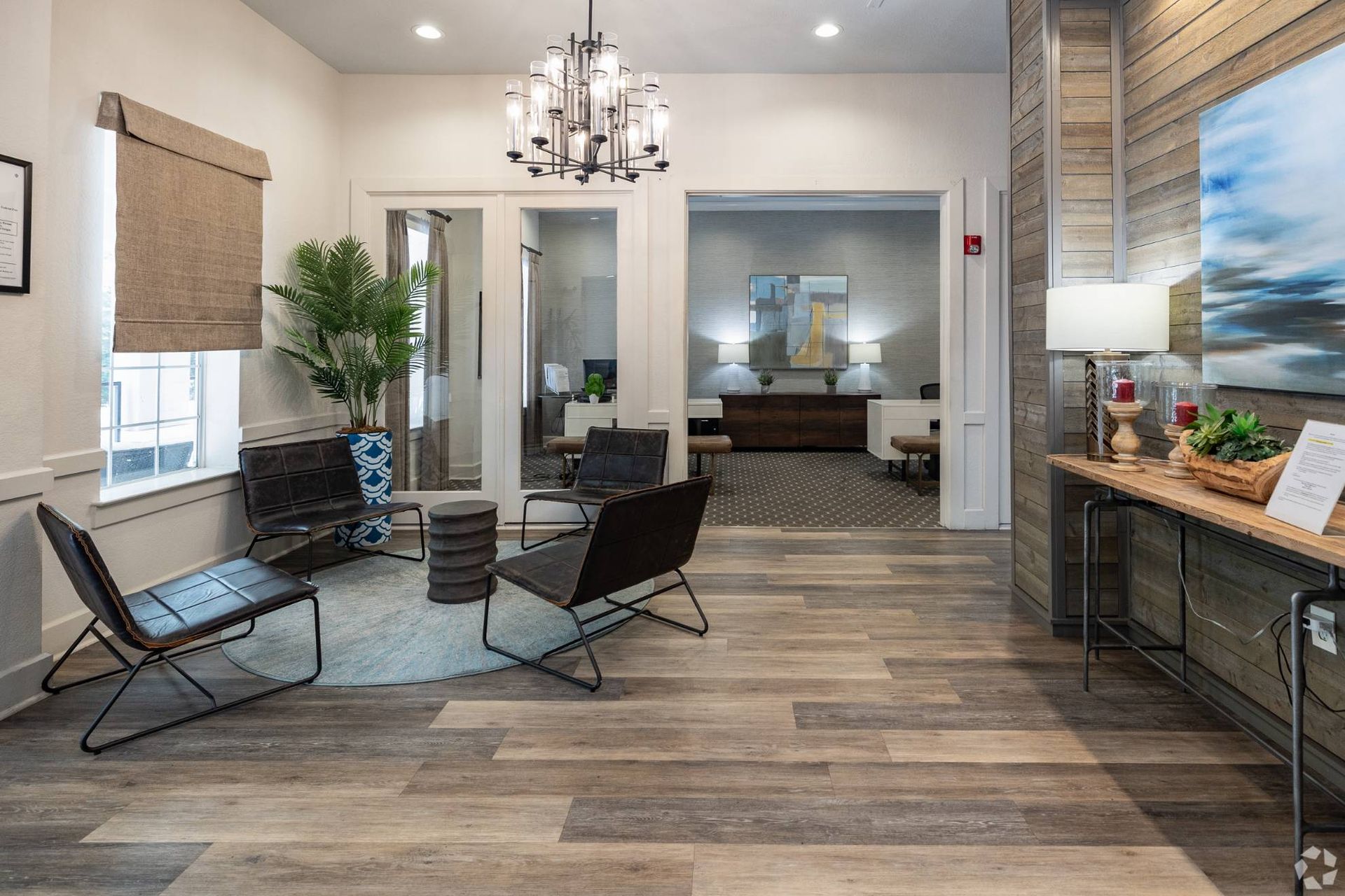 Leasing office lobby with seating, chandelier, and wood-accent walls at Uptown Village Apartments in Gainesville, FL.