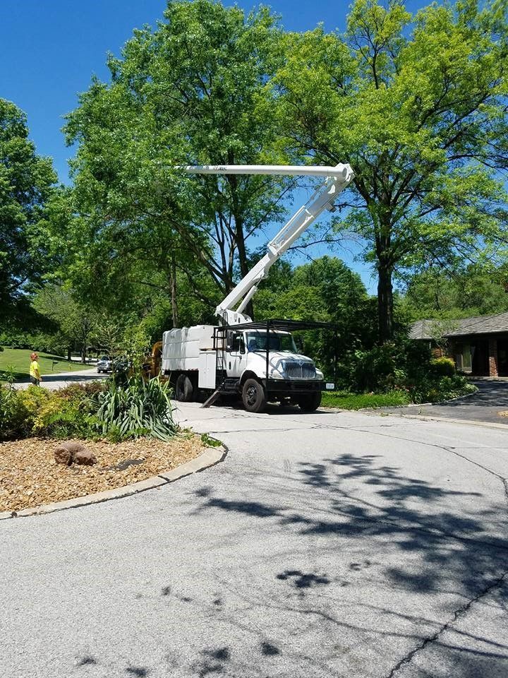 A white truck with a crane on top of it is parked on the side of the road.
