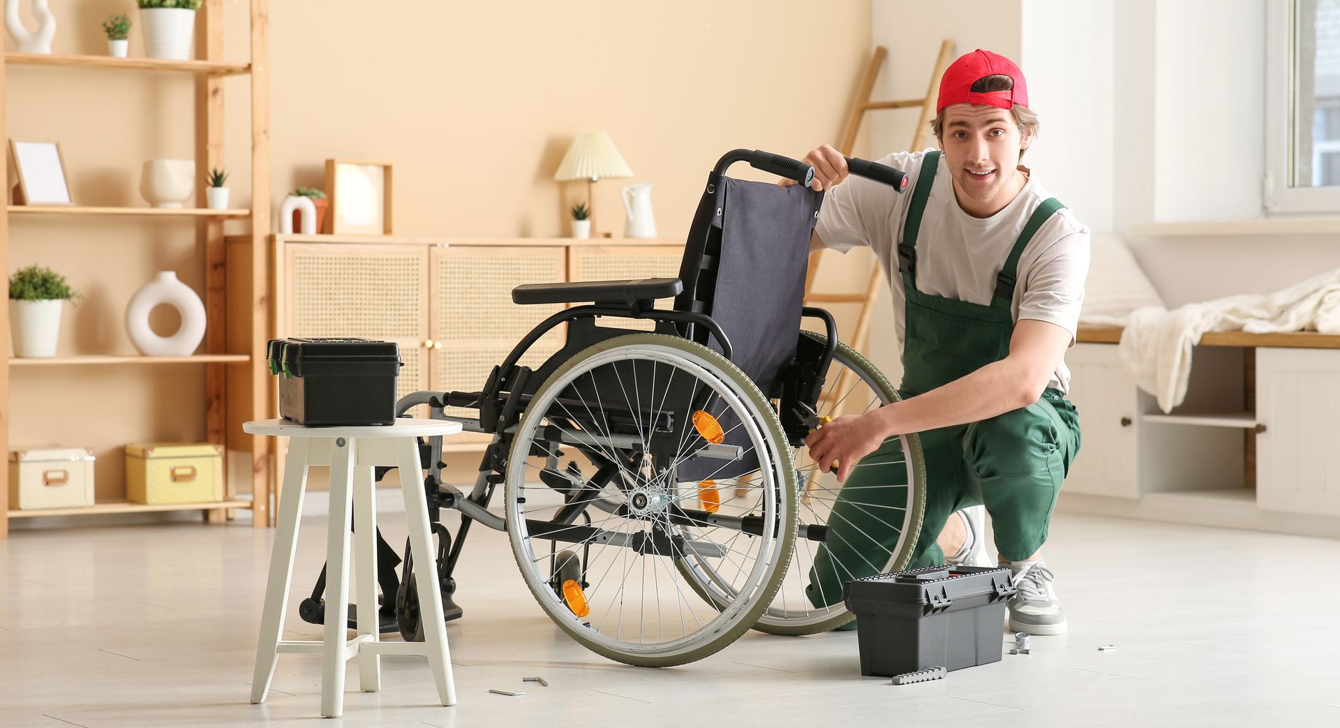 Person repairing a wheelchair in a bright room, with tools and a black toolbox nearby.