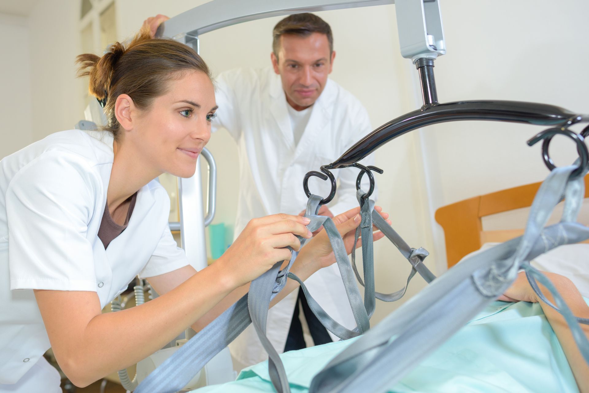 Caregiver assists a person in a mobility lift in a bright bedroom near a window