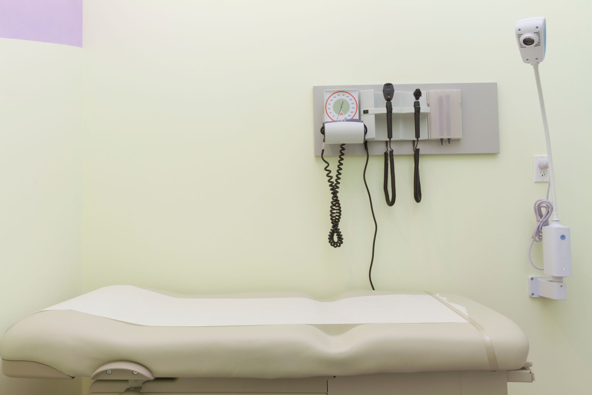 Examination room with an exam table and wall-mounted medical instruments.