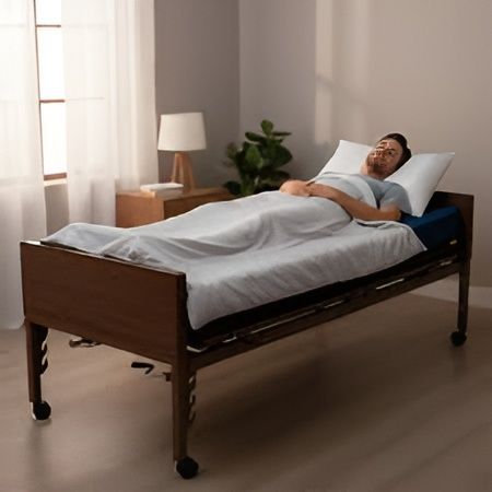 Hospital room with an empty adjustable bed beside a bedside table and window curtains