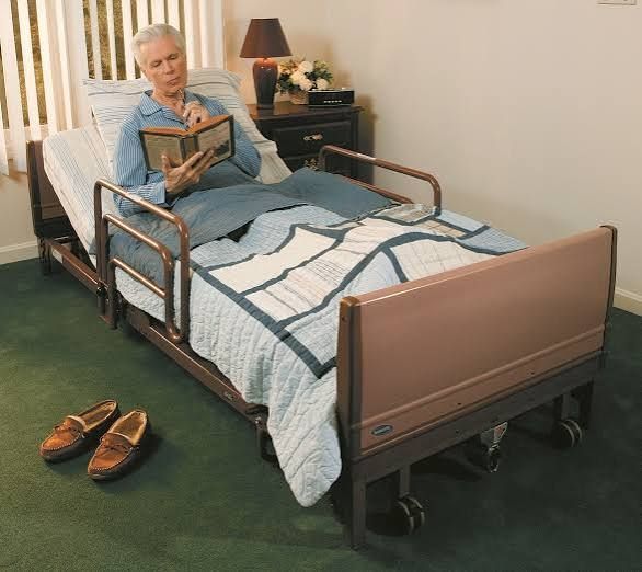 Hospital bed with blue sheets and pillows in a bright, empty room