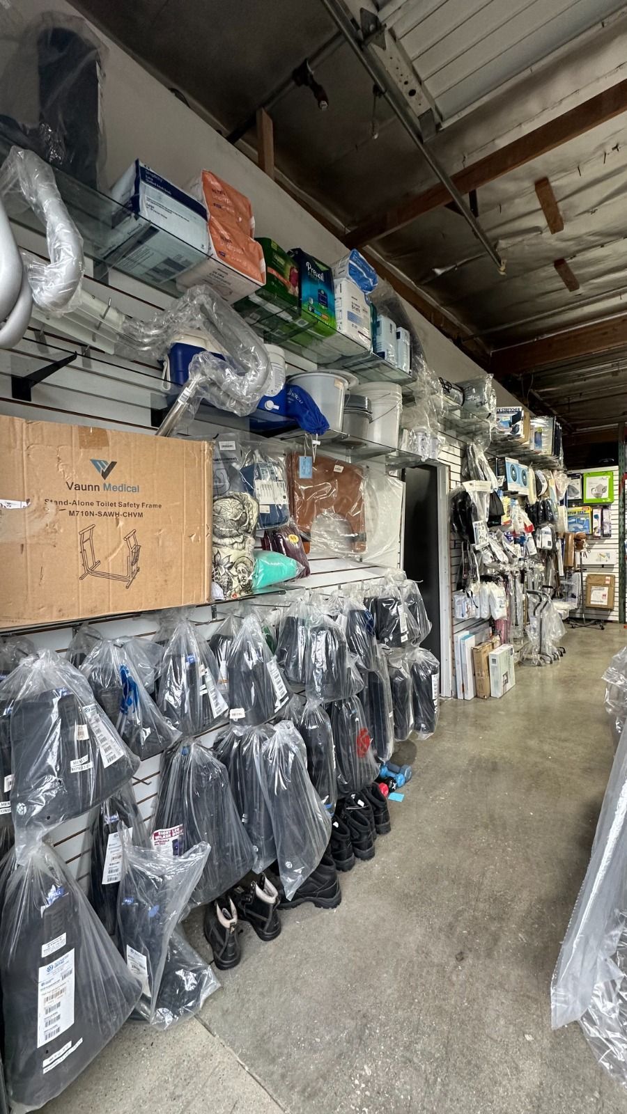 Narrow store aisle with rows of hanging packaged items and shelves stocked to the ceiling