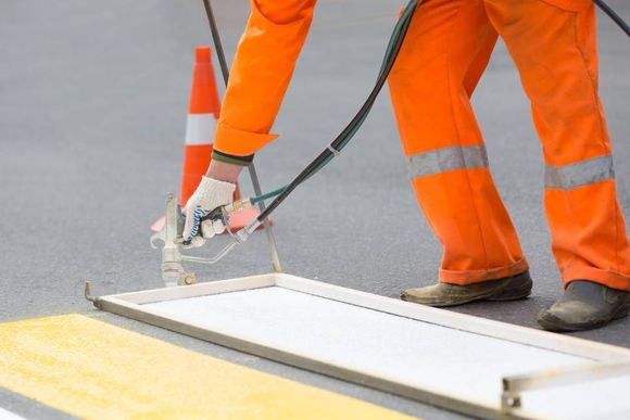 man spray painting a white line