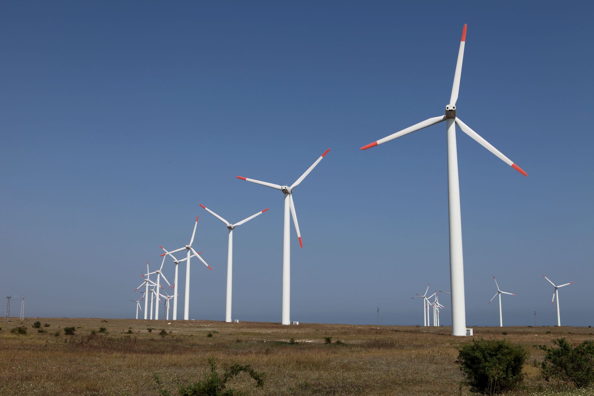 Wind turbines on a field under a clear blue sky. Wind turbines on a field under a clear blue sky.