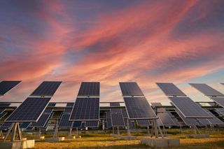 Solar panels angled toward the sky, set against a colorful sunset. Solar panels angled toward the sky, set against a colorful sunset.