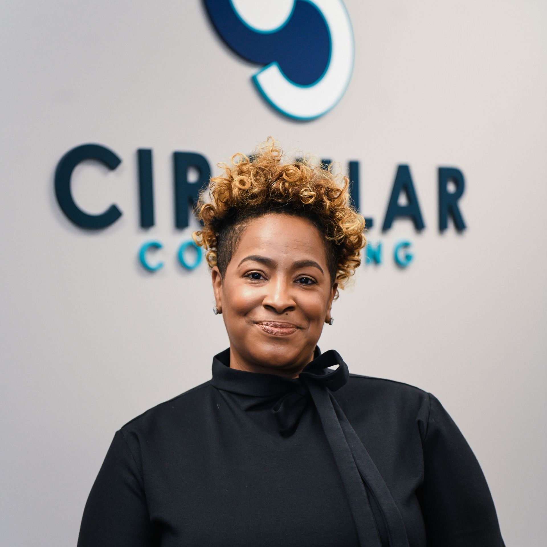 a woman is smiling in front of a circular consulting sign